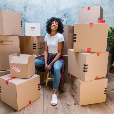A woman surrounded with moving boxes fully packed for moving to NYC.